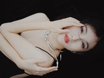 一个年轻女子躺在黑色背景上 手举在空中 正在听音乐。