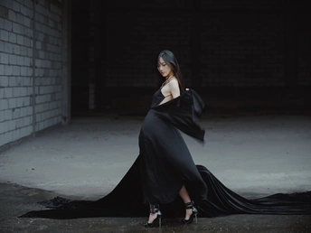 一个穿着黑色长裙 站在黑暗房间里的女人