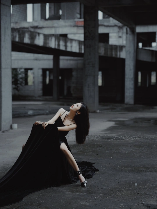 一个穿着黑色长裙的美女在空荡荡的建筑物地板上