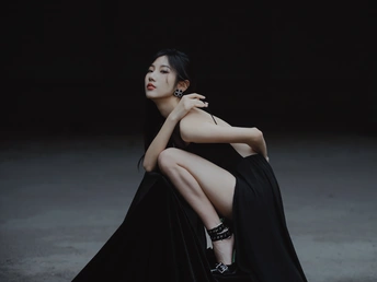 一个穿着黑色连衣裙的年轻女子坐在一个黑暗的房间里