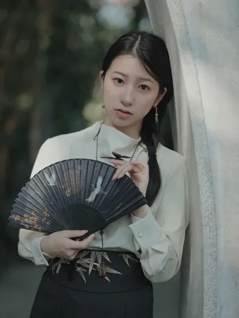 一位穿着日本传统和服的女性拿着扇子站在外面