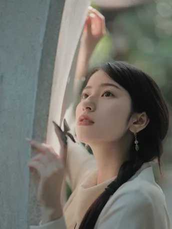 一位站在窗户前的女人 手里拿着剪刀 正对着镜子剪指甲。