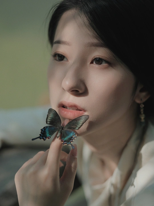 一位年轻女子在鼻子上和手上拿着一只蓝色的蝴蝶拍照