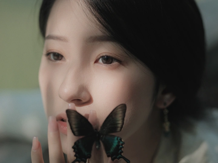 一位年轻女子手里拿着一对耳环 将一只黑蝴蝶举到她面前