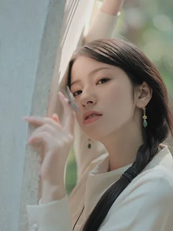 一位年轻女子穿着白色衬衫 正在看窗户外面的景色。