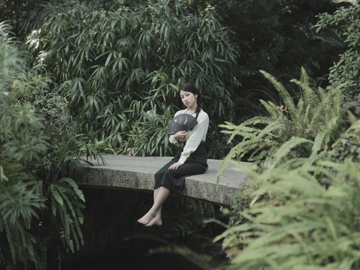 一位坐在水上的桥上的女人