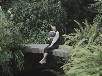 一位坐在水上的桥上的女人