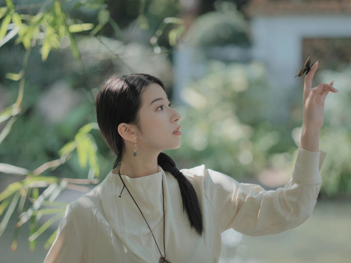 一位穿着全白的年轻女子手里拿了一只鸟