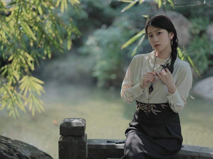 一位年轻女子坐在池塘边的长椅上