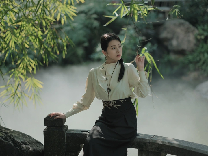 一位年轻女士坐在河上的一座桥的岩石上