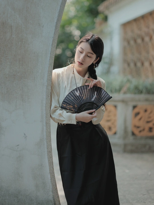 一位穿着传统裙子的年轻女子拿着扇子