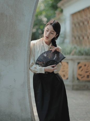 一位穿着传统裙子的年轻女子拿着扇子