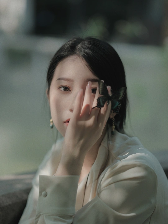 一位年轻女子坐在靠近她脸颊的地方 手上有一只蝴蝶。