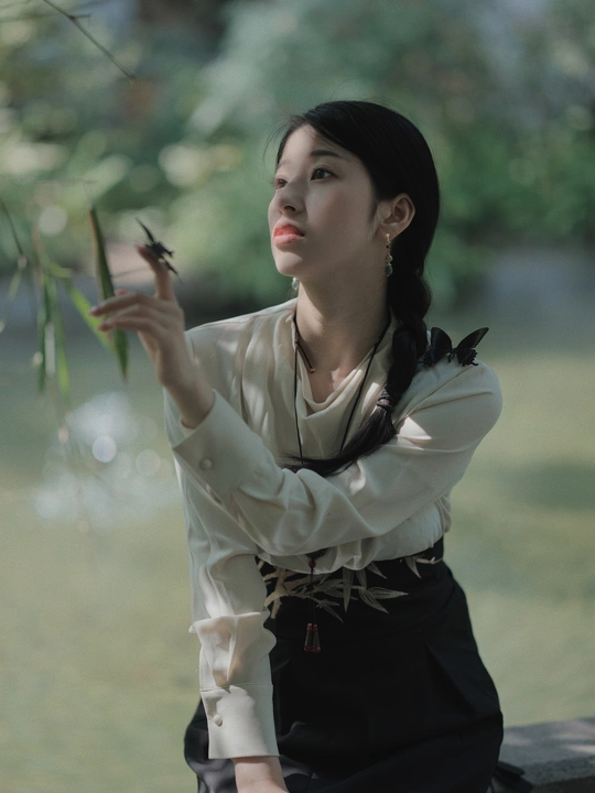 一位年轻女子手持手机坐在树下