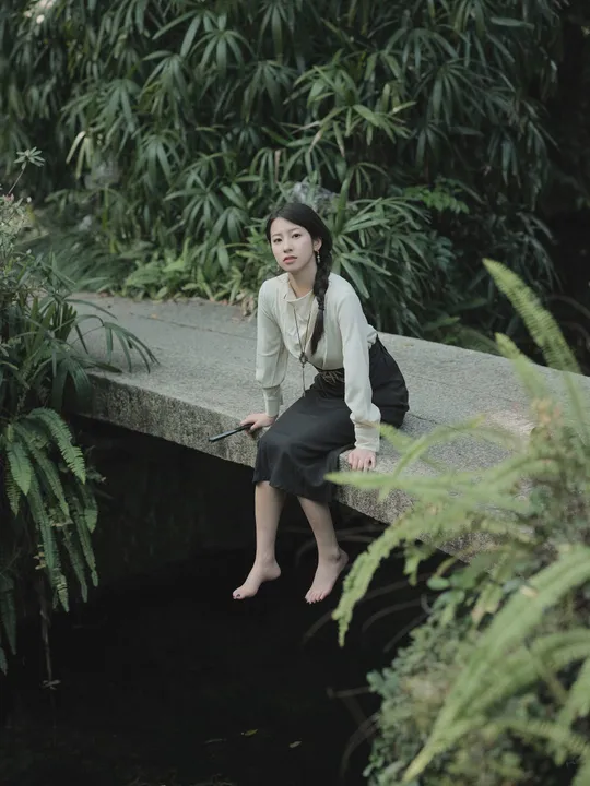 一位女性坐在一条小溪上的桥上