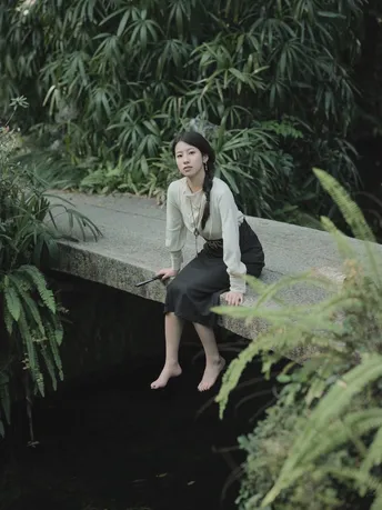 一位女性坐在一条小溪上的桥上