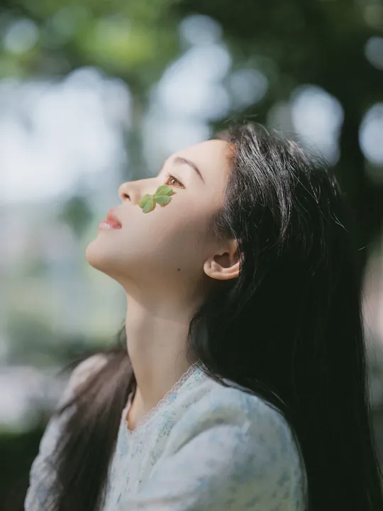 一位年轻女子仰望着天空 眼中带着一片树叶。