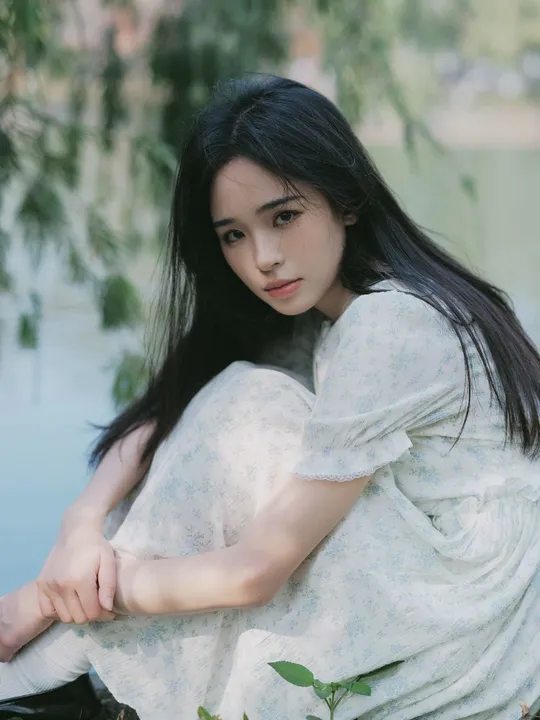 白色连衣裙的年轻美女坐在湖边