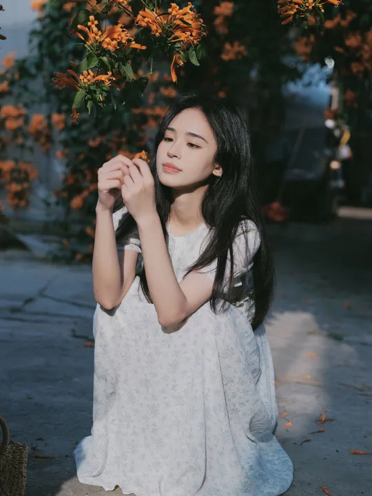 一个穿着白色连衣裙的年轻女子坐在有花的树下