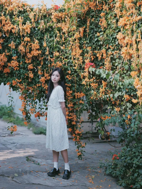 站在开满花的树下的穿着白裙子的年轻女子