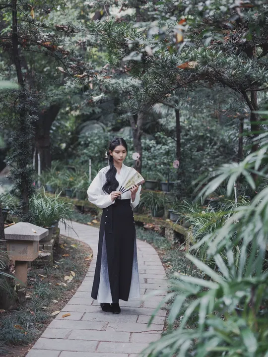 一位穿着和服的女士拿着雨伞走在小径上