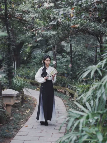 一位穿着和服的女士拿着雨伞走在小径上