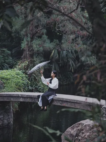 一位女士在河上的桥上拿着一把伞