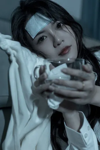 一个年轻女子手里拿着一杯水 躺在地上。
