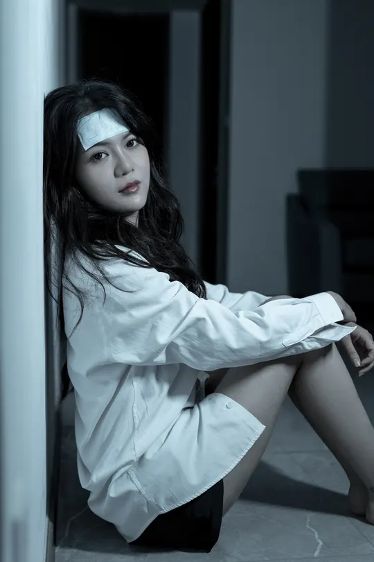 一个穿着白衬衫的年轻女子坐在地板上 靠墙