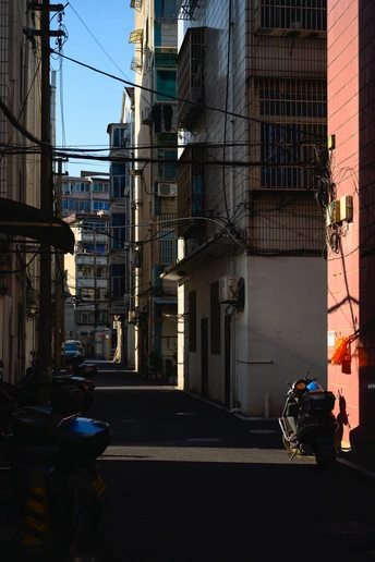 城市里一条狭窄的小巷 有高楼大厦 路边停着一辆摩托车