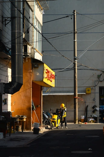 一名男子走在一栋挂着黄色标志的建筑旁的街道上