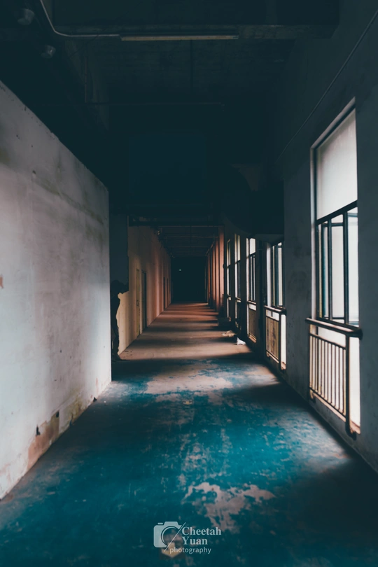 一条长长的空荡走廊 地板是蓝色的 窗户透进来光