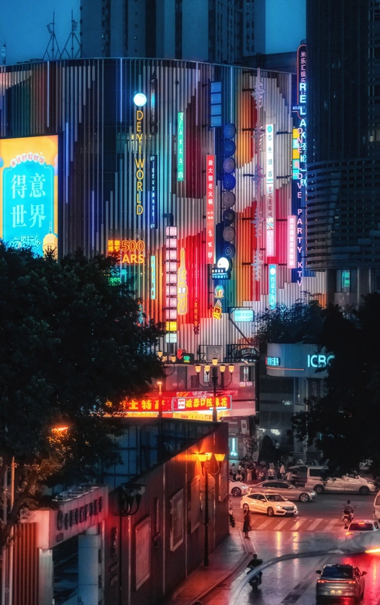 夜晚的城市街道 高耸的建筑物 明亮的灯光 街道上行驶的汽车。