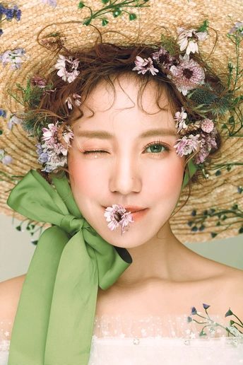 一位年轻女子穿着一件白色连衣裙和一顶绿色帽子 头戴花环。