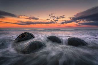 一片水面 远处有波浪和岩石 夕阳西下