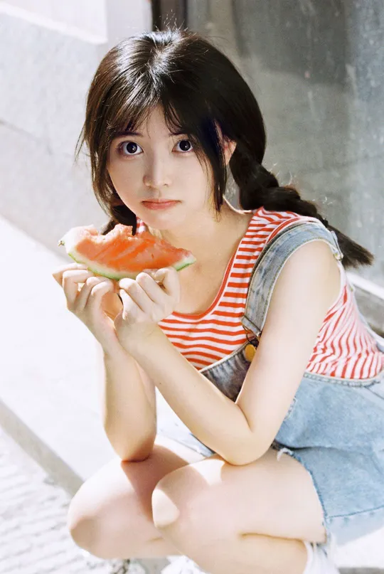 一位年轻女子坐在地上 手里拿着一颗小水melon。