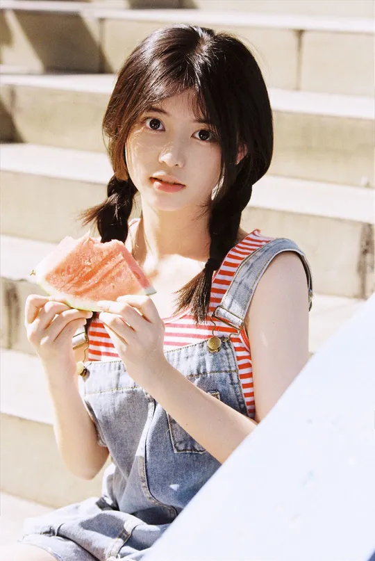 一个年轻女子坐在台阶上吃西瓜。