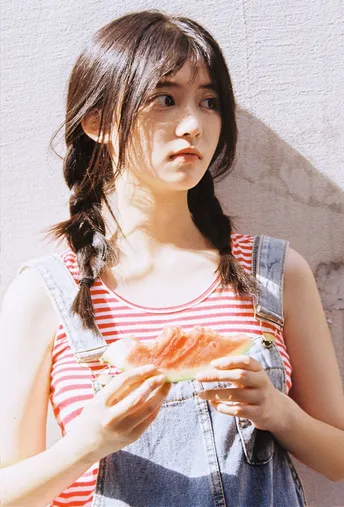 一个小女孩穿着条纹裙 手里拿着一个西瓜。