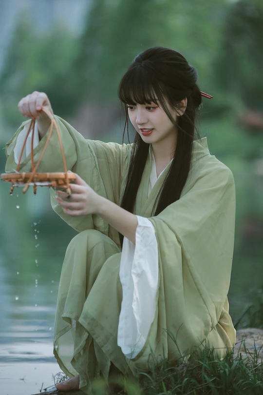 一位穿着绿色和服的年轻女子抱着篮子坐在水中