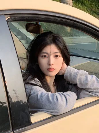 一位年轻女子坐在汽车里 透过窗户向外看 还有另一个人在车窗外