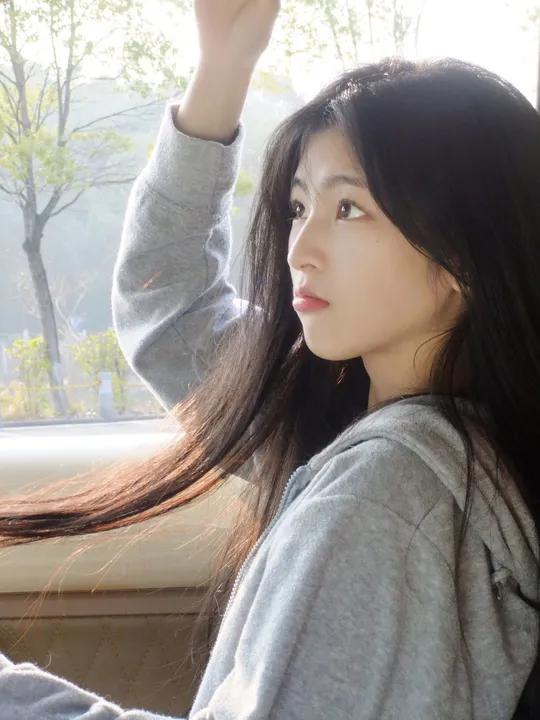 一个年轻女子坐在窗前 手插在头发里