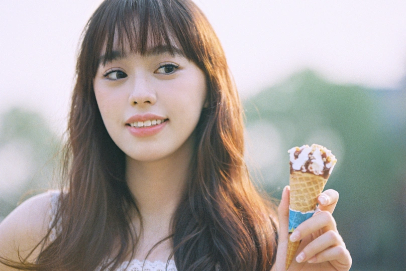 一位年轻女子手里拿着一支冰淇淋 cone。