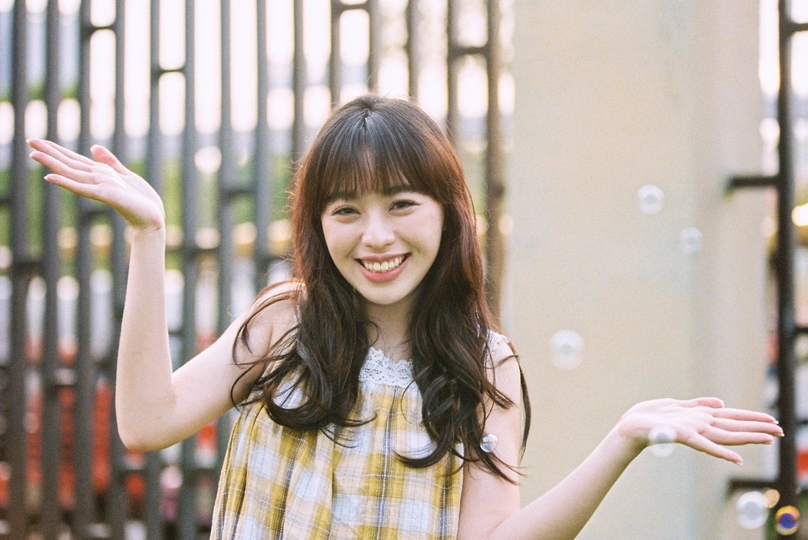 一位穿着黄色和白色格子裙的年轻女子张开双臂将飞盘扔向侧面。