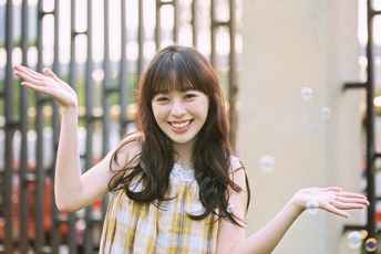 一位穿着黄色和白色格子裙的年轻女子张开双臂将飞盘扔向侧面。