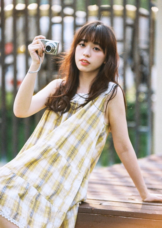 一个穿着黄色格子裙子的年轻女子正在用相机拍照。