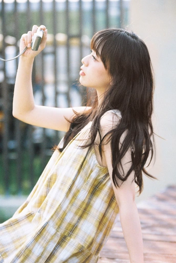 一位穿着黄色格子裙的年轻女子手持相机