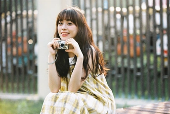 一位穿着黄色连衣裙的年轻女子手持相机拍照