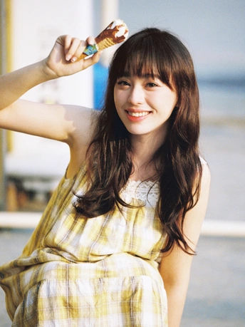 一位穿着黄裙子的年轻女子站在海滩上