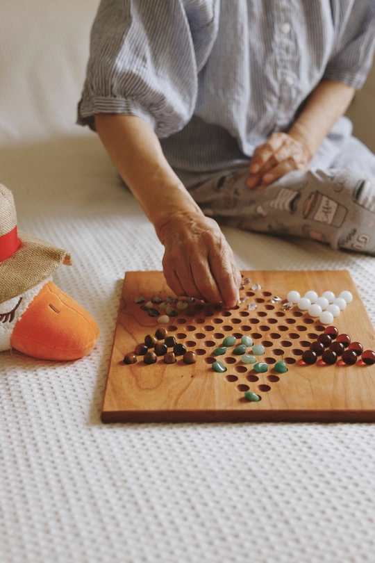 一位戴着帽子的老妇人坐在床上 在木板上玩游戏