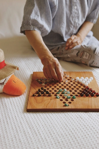 一位戴着帽子的老妇人坐在床上 在木板上玩游戏